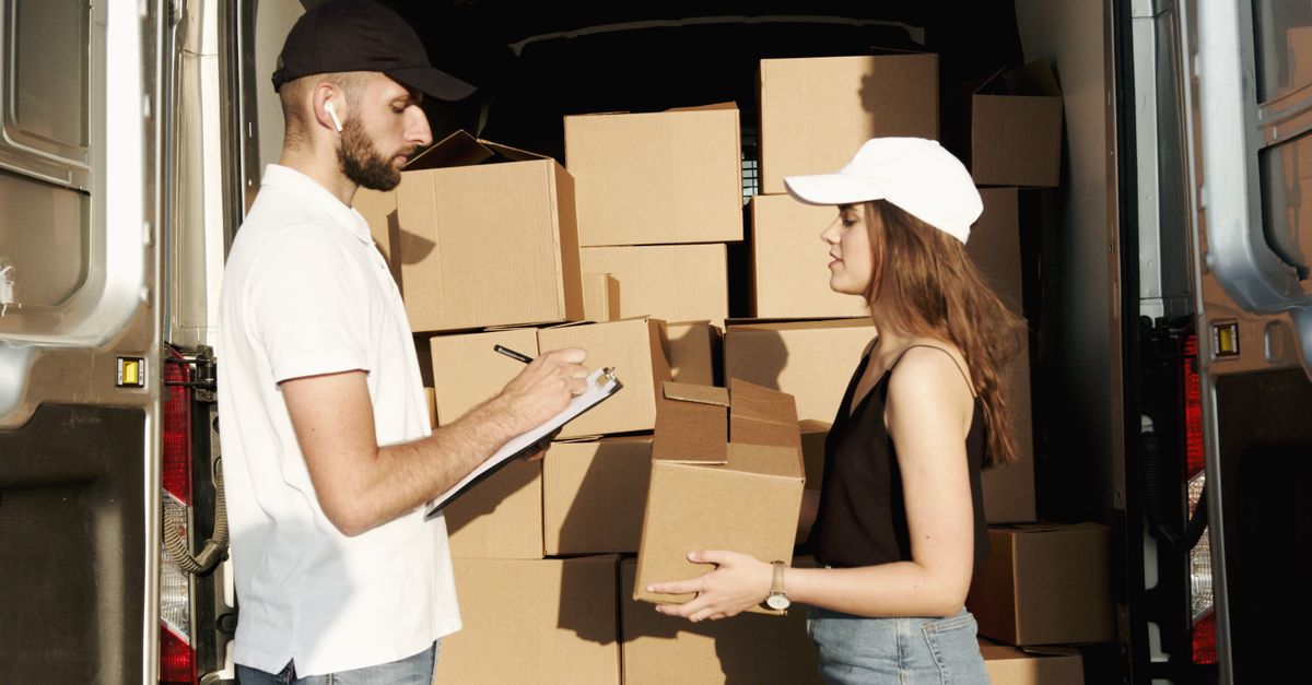 A male and female courier organizing packages in a delivery truck for efficient shipment.
