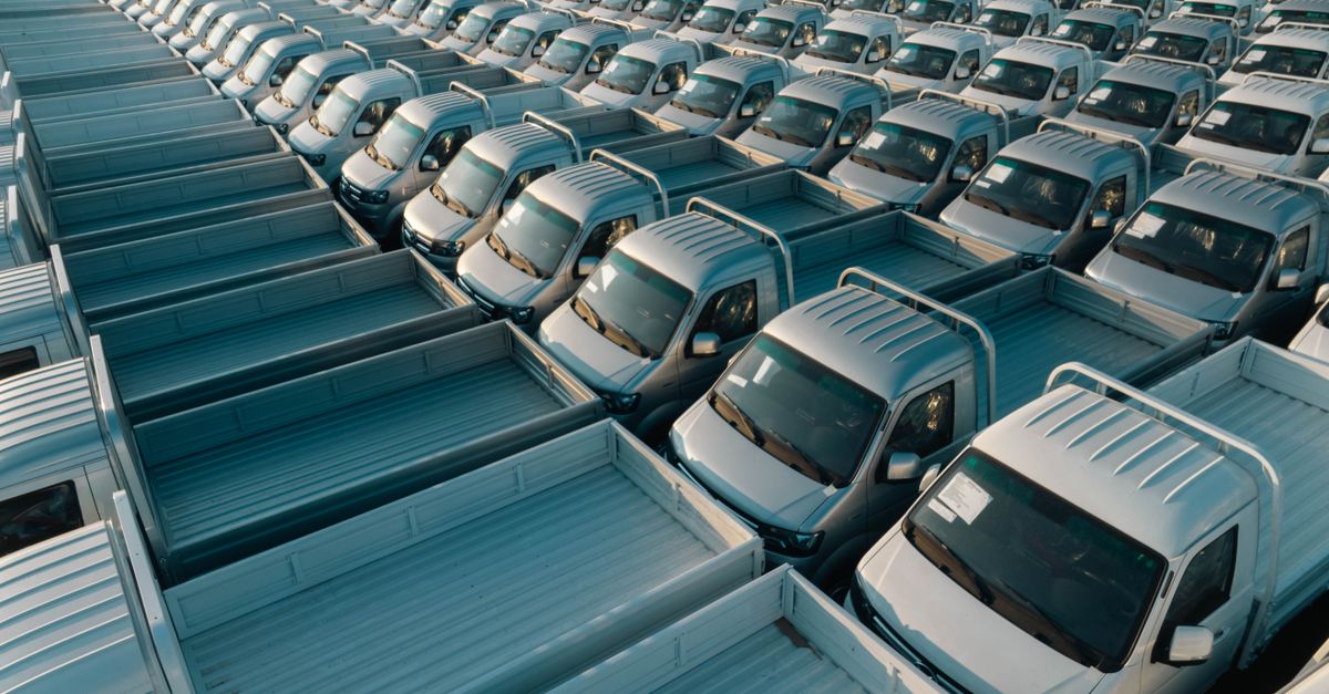Aerial perspective showcasing a vast array of new silver pickup trucks parked in an orderly fashion.